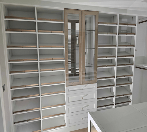 custom walk in closet with shoe shelves and shoe fence and glass doors