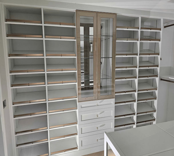 custom walk in closet with shoe shelves and shoe fence and glass doors