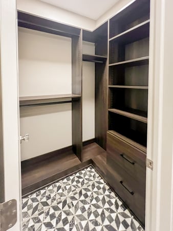 Mudroom walk in closet with a dark brown finish. Complete with hanging, open shelving, and drawers.