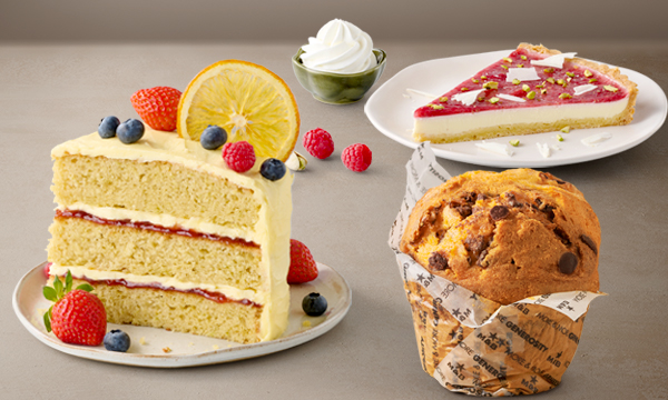 Freshly baked cakes and treats from Mugg & Bean Kenilworth Centre including a Choc Chip Giant Muffin, Berry & Lime Cake Slice, and Raspberry & Pistachio Panna Cotta Tart Slice.