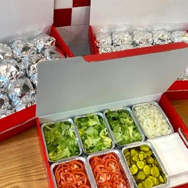 Catering boxes of Five Guys burgers and toppings.