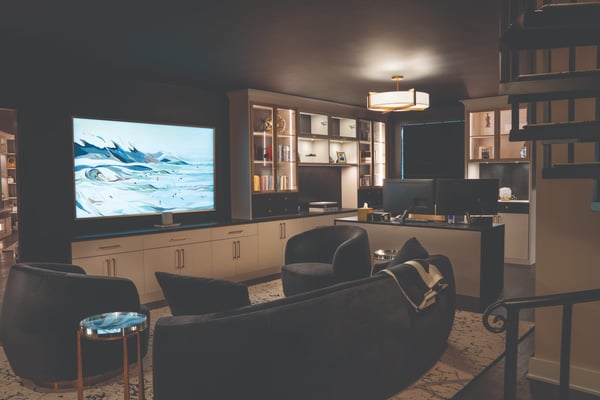 Luxury home office featuring custom built-in cabinetry, illuminated shelving, an executive desk, and comfortable seating area.