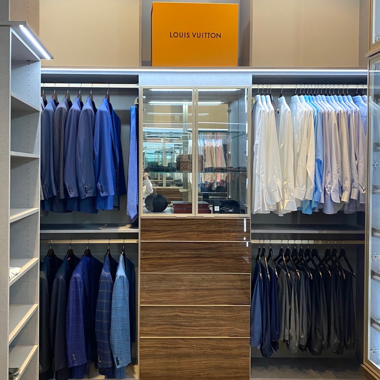 Dark brown men's closet organization with lighting and island  by California Closets Baton Rouge, Louisiana.