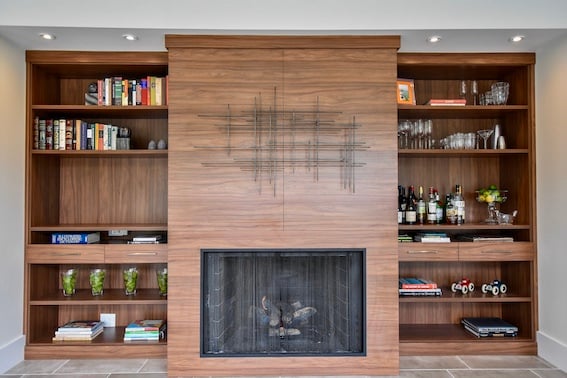 A contemporary fireplace-surround design with wine storage and wrapped paneling.