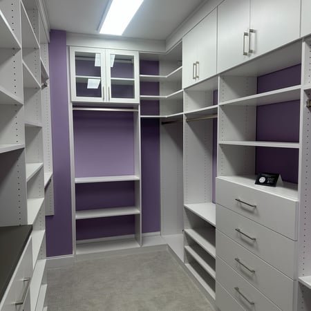 Greensboro - Custom closets - purple walk-in closet with white shelving, drawers, cabinets, and a glass cabinet for display items