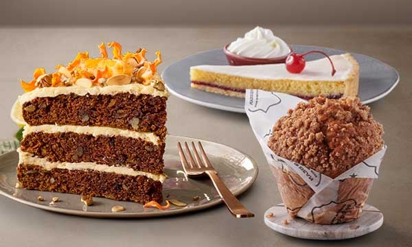 Freshly baked cakes and treats from Mugg & Bean King Shaka Airport International including a Spiced Apple Crumble Giant Muffin, Cherry Bakewell Tart, and Carrot Cake.