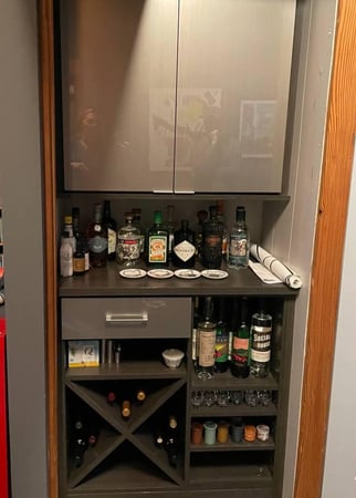 A wine and spirits bar featuring a counter, cabinets, and open shelving.
