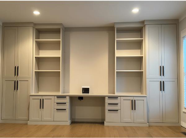 Light home office with desk in center and cabinets surrounding on both sides