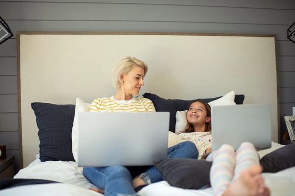 Madre e hija usando computadoras portátiles en el dormitorio