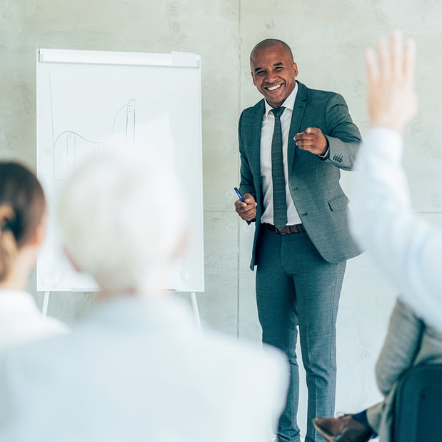 A man in a suit pointing to a person holding up their hand