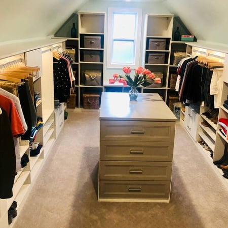 A walk-in closet featuring an island of drawers in the center.