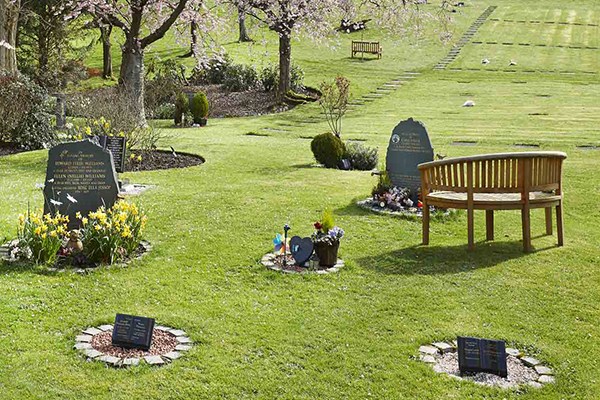 A memorial bench and assorted cremation memorials, set out in the Gardens of Rememb