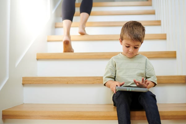 Kid sitting on stairs while playing on tablet