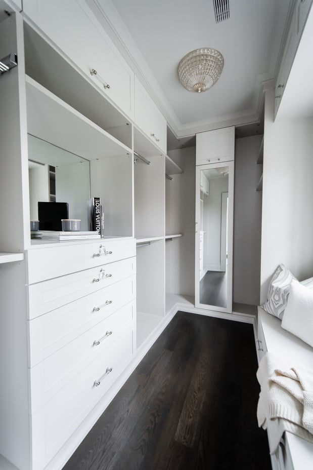 White walk-in closet with built-in drawers, window bench, and shoe shelves.
