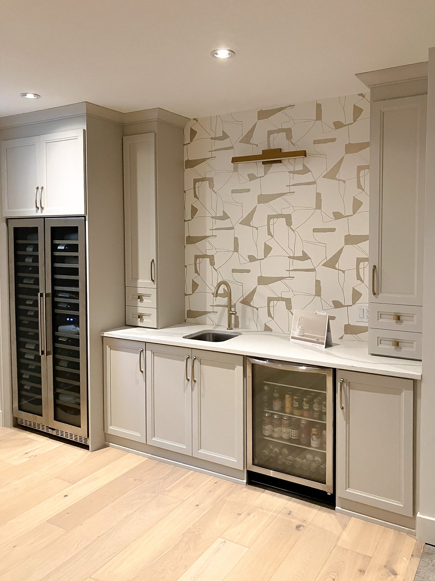 A traditional bar system designed in a gray cabinetry with gold hardware.