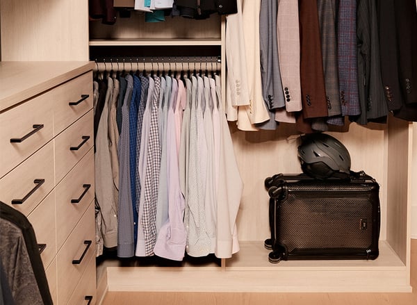 Custom walk-in closet by California Closets Nashville with double hanging storage, built-in drawers, shelving and dedicated luggage storage.