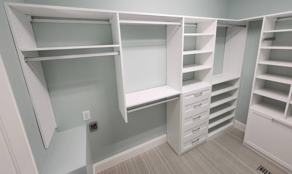 A large closet featuring hanging racks, shelves, and drawers.
