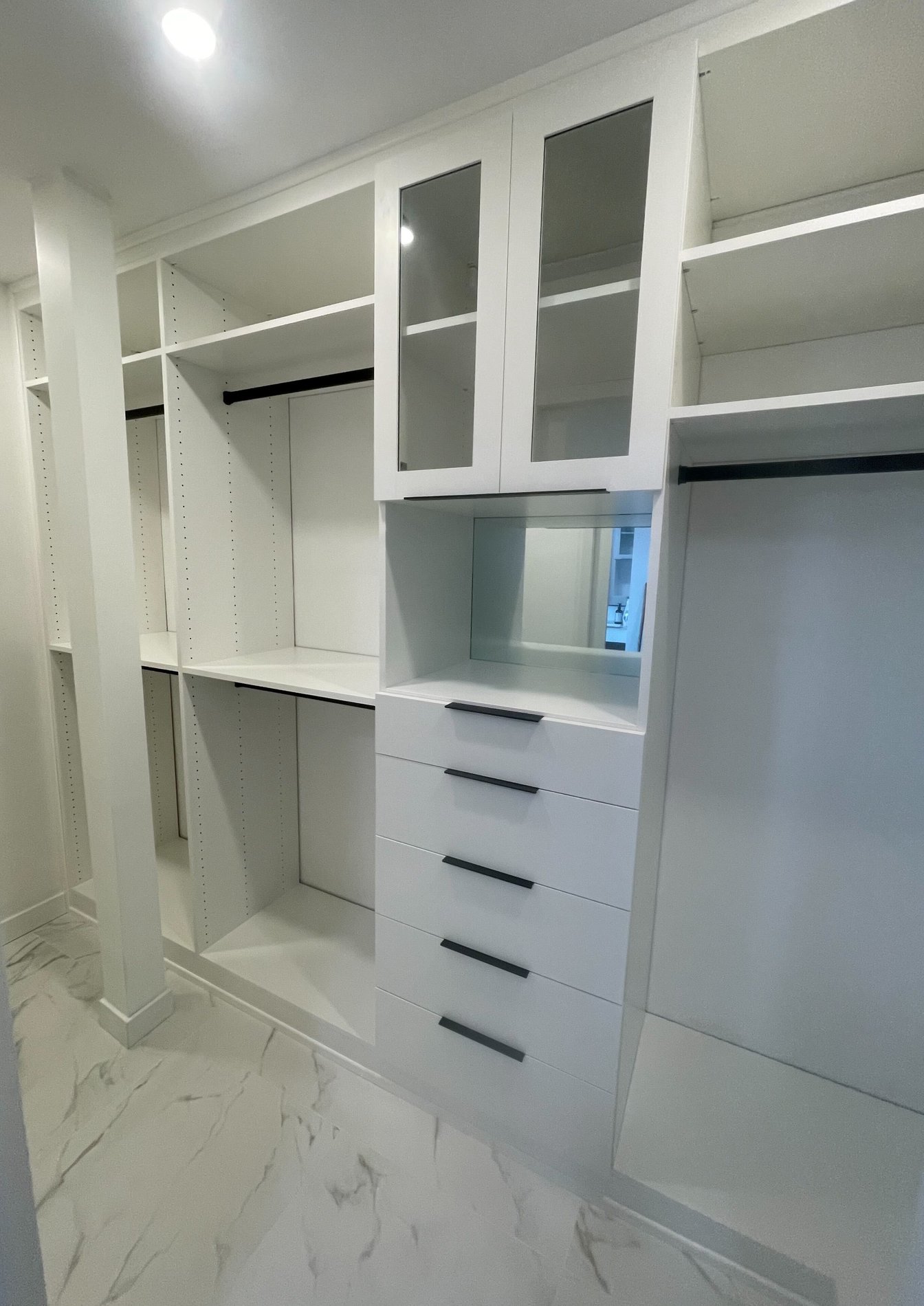 Dove walk-in closet shelves, drawers and hanging rods with a beautiful shaker style doors with low iron glass inserts.