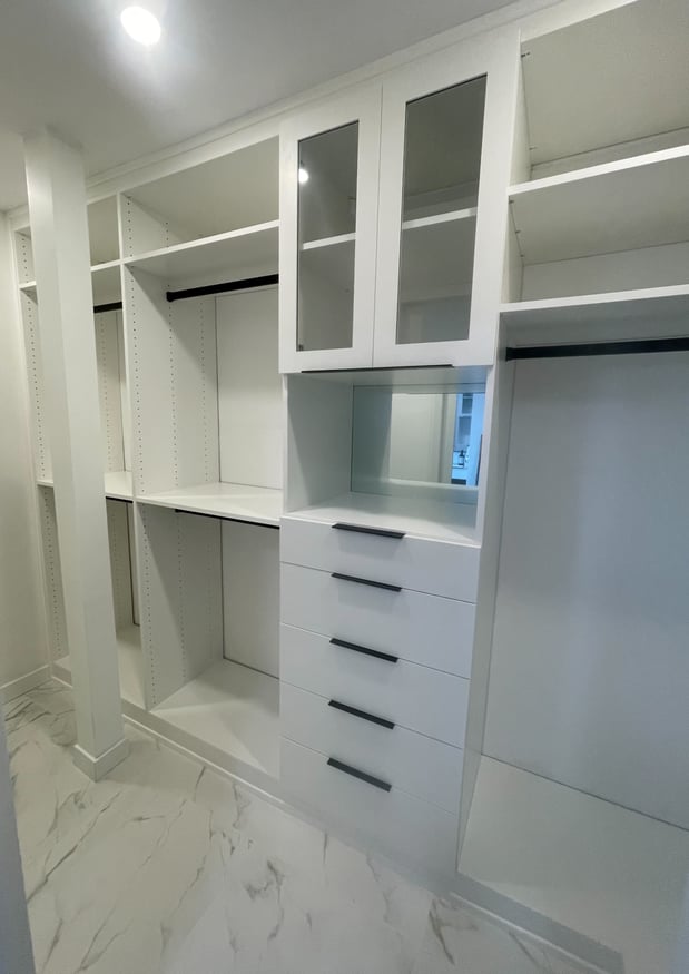 Dove walk-in closet shelves, drawers and hanging rods with a beautiful shaker style doors with low iron glass inserts.