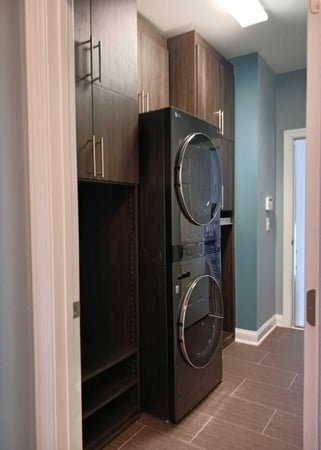 A laundry room outfitted with cabinets and a stackable washer and dryer.