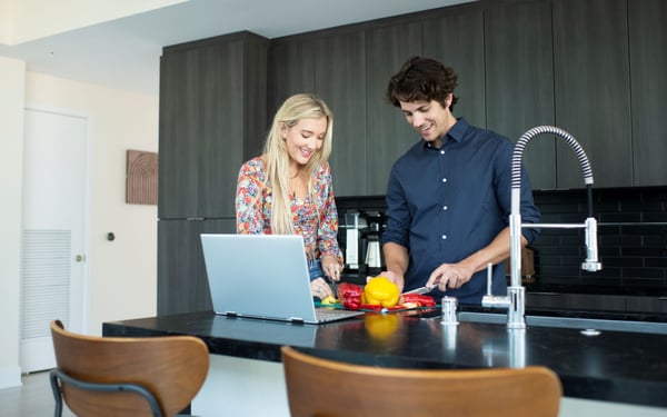 Couple streaming cooking show in the kitchen, using fiber internet