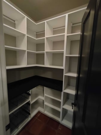 Walk in pantry that has a lot of shelving, and a black countertop and baskets