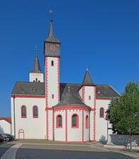 Frontansicht der Kirche. Die prägenden Farben sind rot und weiß, während das Dach in schwarz gehalten wurde.