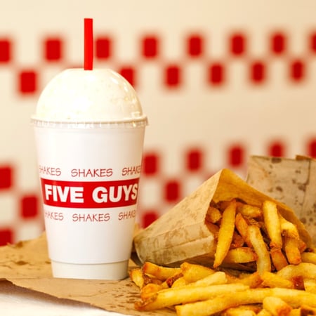 A close-up image of a Five Guys milkshake, with fries.