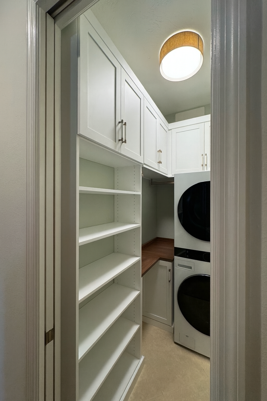 Custom laundry room in white finish with Sienna countertop, gold hardware, and winter leather wrapped handles.
