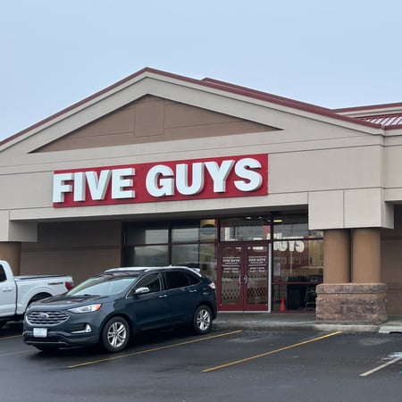 Exterior photograph of the entrance to the Five Guys restaurant at 9502 North Newport Highway in Spokane, Washington.