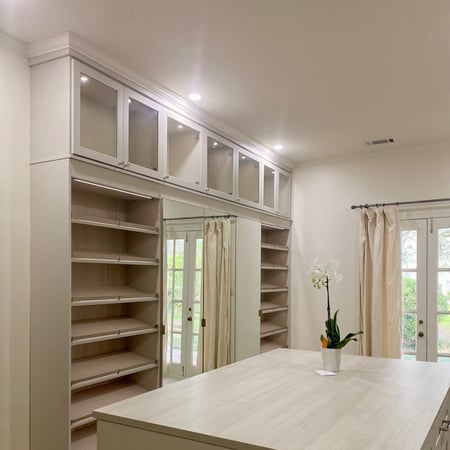 Light gray walk-in closet organization with island and shoe shelving California Closets New Orleans & Gulf Coast