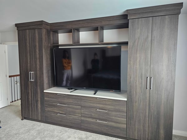 Custom brown Entertainment center with a TV, has drawers, doors, and shelves