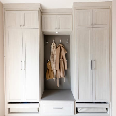 Mudroom with floor to ceiling storage, pull out baskets, a small bench and hooks.