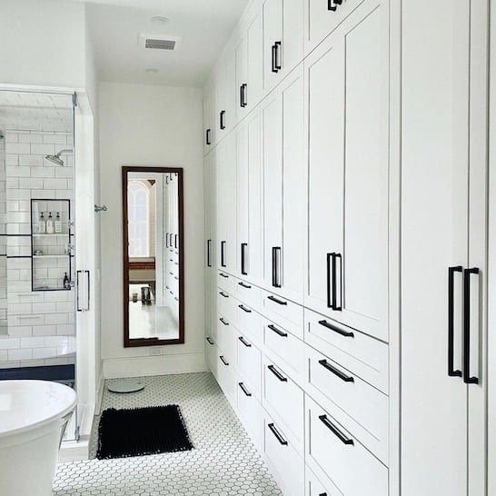 White bathroom cabinets with black hardware.
