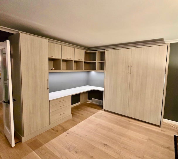 Light wood Murphy bed with integrated home office, custom shelving, drawers, and built-in cabinets for space-saving organization in Grosse Pointe Shores, Michigan
