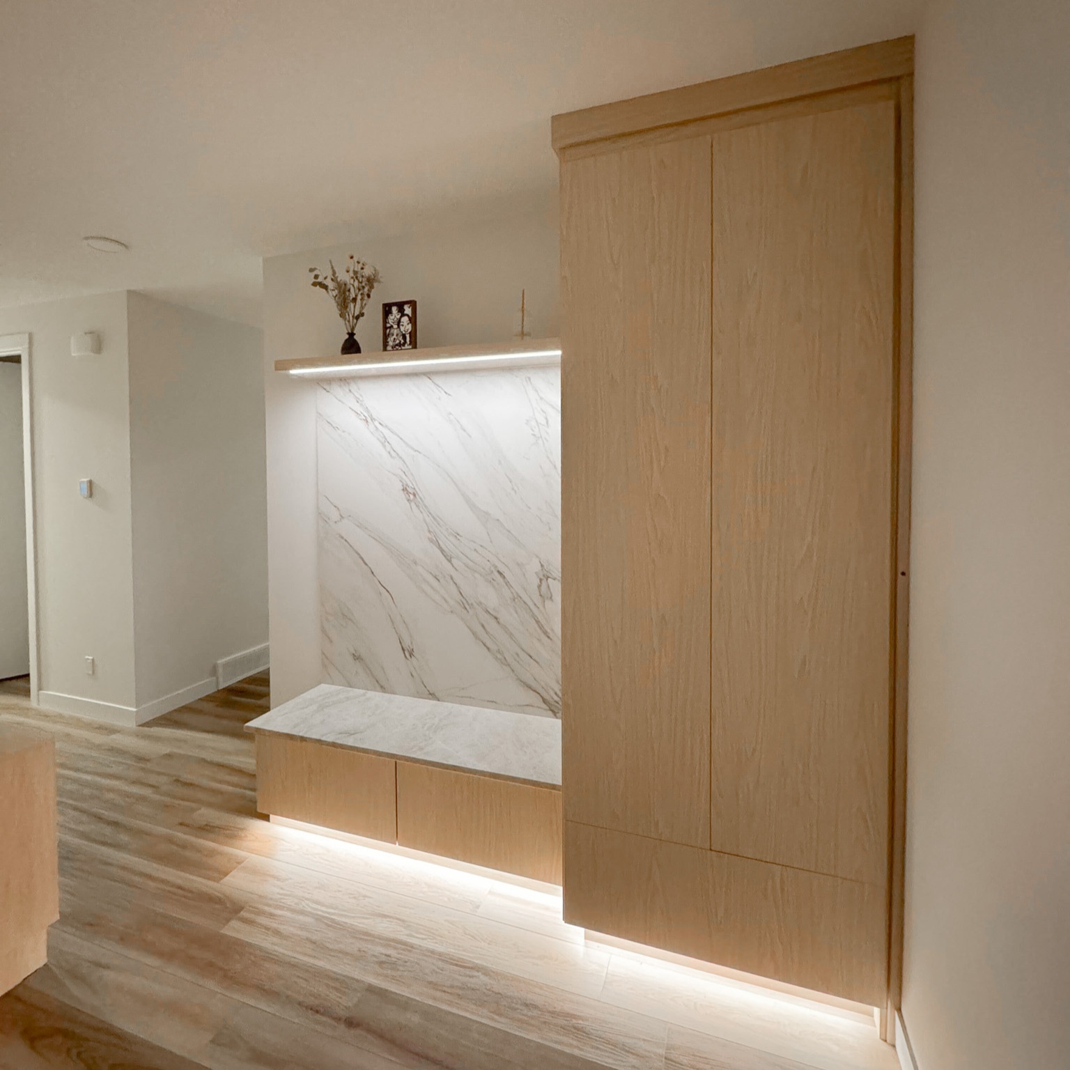 Mudroom with floor to ceiling storage, floating shelf, bench, and toe kick lighting.