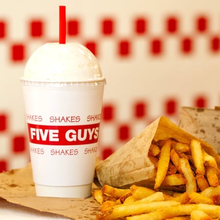 Une image en gros plan d'un milk-shake Five Guys, accompagné de frites.
