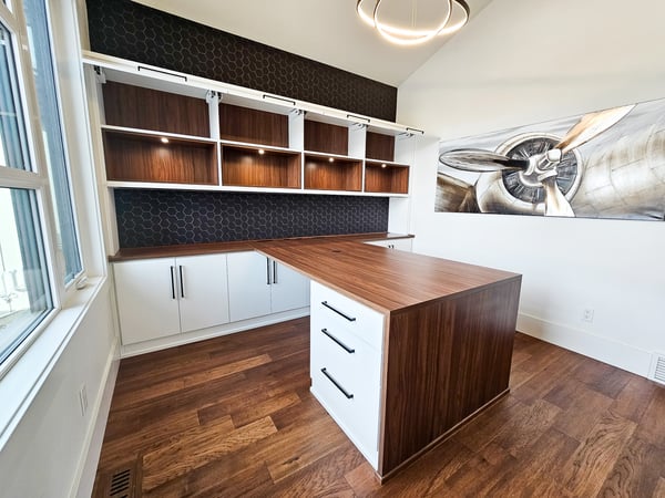 A warm and inviting home office with warm woods, bright white cabinets, open shelves and lighting.