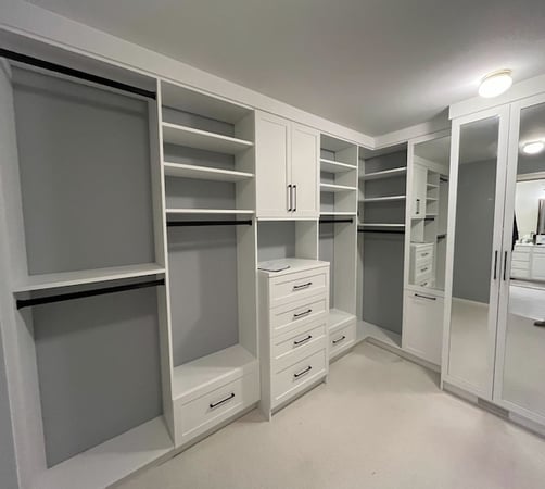 white custom walk-in closet with shelves, hanging rods, and mirrored doors