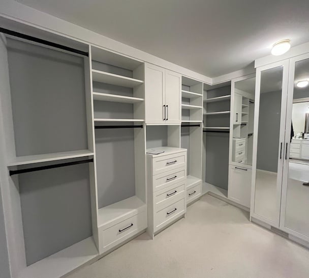 white custom walk-in closet with shelves, hanging rods, and mirrored doors