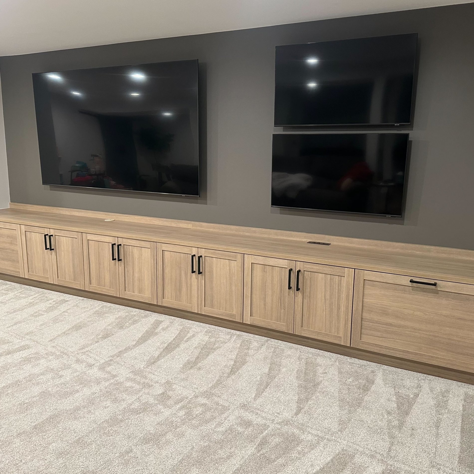 Custom media center with wood cabinets and wall-mounted TVs.