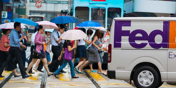 A picture containing people, umbrellas, road and FedEx van