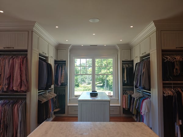 Large walk-in closet with hanging clothes, island and window