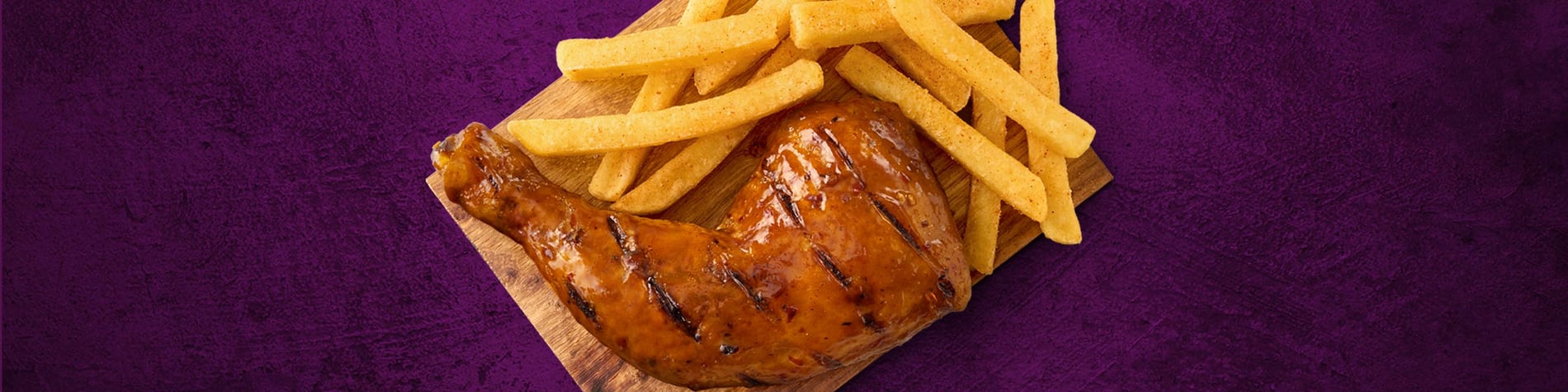 A quarter chicken and a side of chips on a wooden board that’s placed on a purple background.