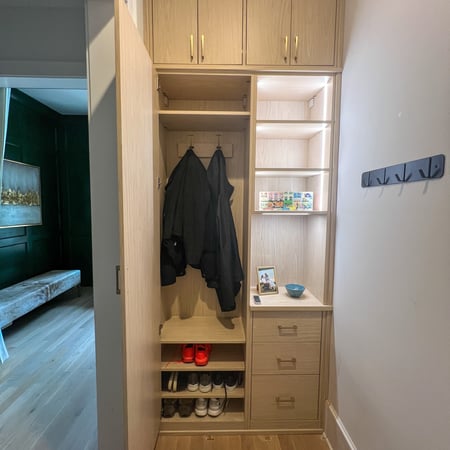 Organize your backpacks, purses, jackets, and more with a custom mudroom! This system is in the Natural finish with gold hardware and lighting inside of partitions and shelves.