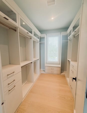 Custom linen primary closet with gold hardware, flip-up doors, and fluted rods.