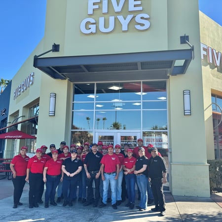 Employees pose for a photograph outside the entrance to the Five Guys restaurant at 4930 Dublin Boulevard in Dublin, California.