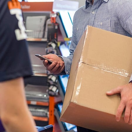 FedEx employee and a customer holding a box and phone