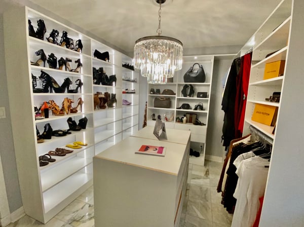 White walk-in closet with a chandelier and shoe shelving