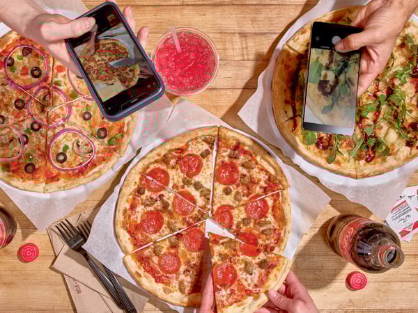 Three masterpiece pizzas, a meat pizza, a veggie pizza, and a posh gourmet pizza are sitting on a table outside.